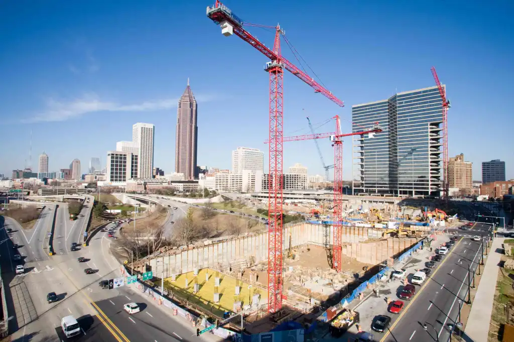 Photograph of a construction site with cranes and some skyscraper buildings in the background.