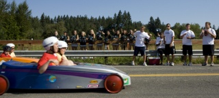 Two participants in Saturday's Sammamish Challenge Day Race approach the finish line as Skyline cheerleaders and football players root them on.