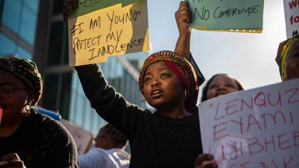 Demonstrators holding signs advocating for the stop of gender-based violence in South Africa. 