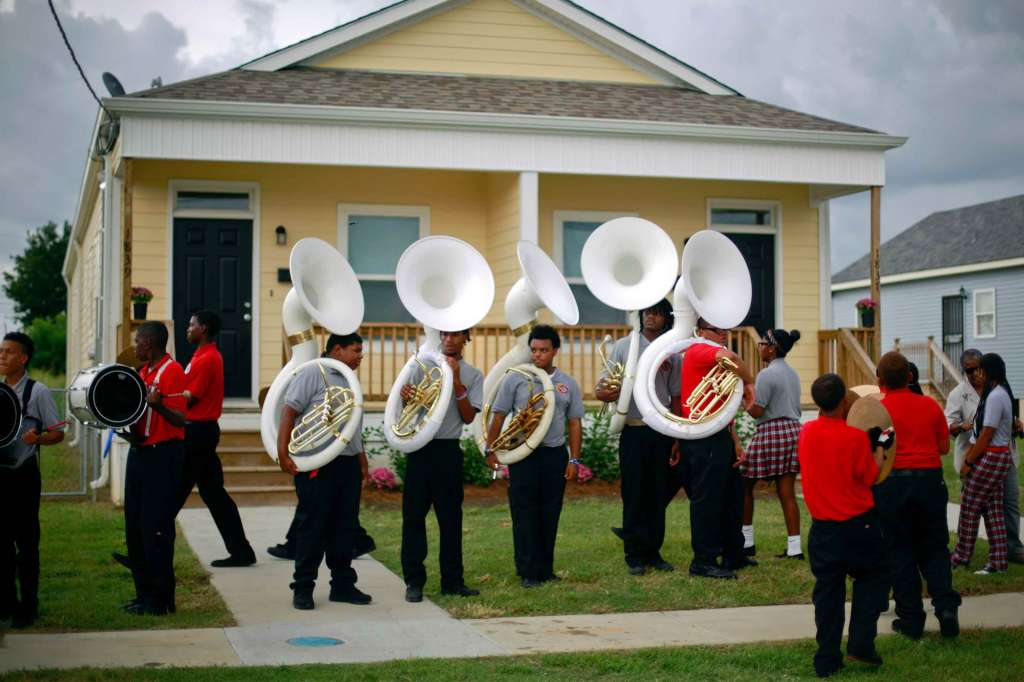 Group of High School Marching Band members holding musical instruments and wearing red or gray t-shirts.