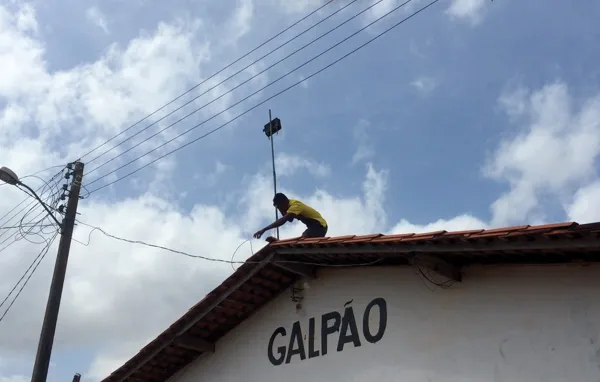 Person setting up wireless antenna on roof in an indigenous community in Brazil.