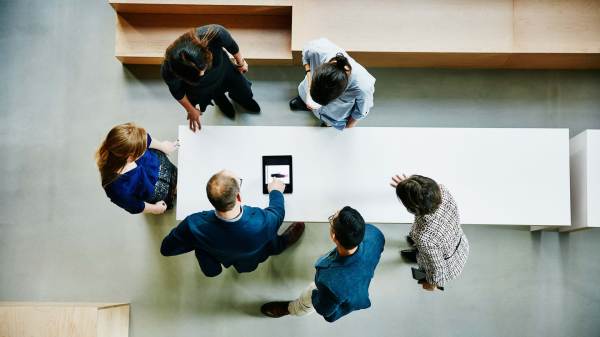 Overhead view of business colleagues discussing a project on a digital tablet.