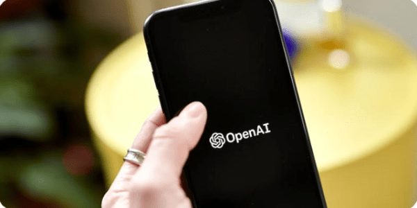A hand holding a cellphone. The screen is completely black the Open Ai logo in the center.